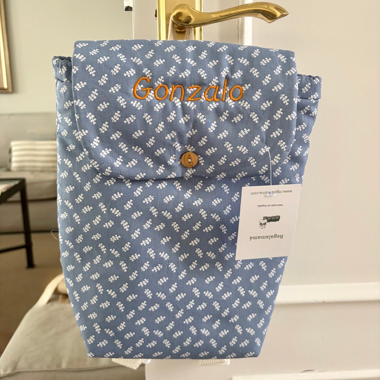 Mochila de guardería personalizada con el nombre, impermeable por dentro, y de un estampado azul de ramitas.