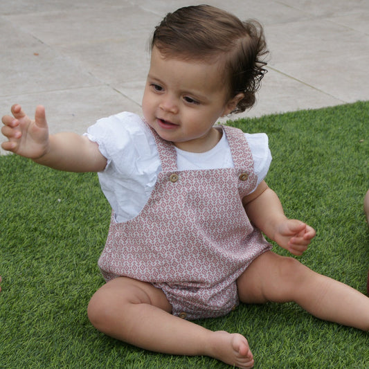 Foto de un bebé con un peto de estampado color blanco y granate