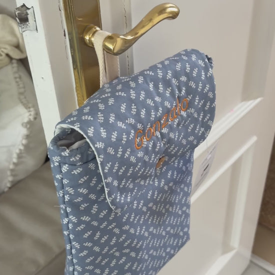 Video al detalle de la mochila para la guardería impermeable por dentro, personalizada con el nombre, y de un estampado de ramitas azul.