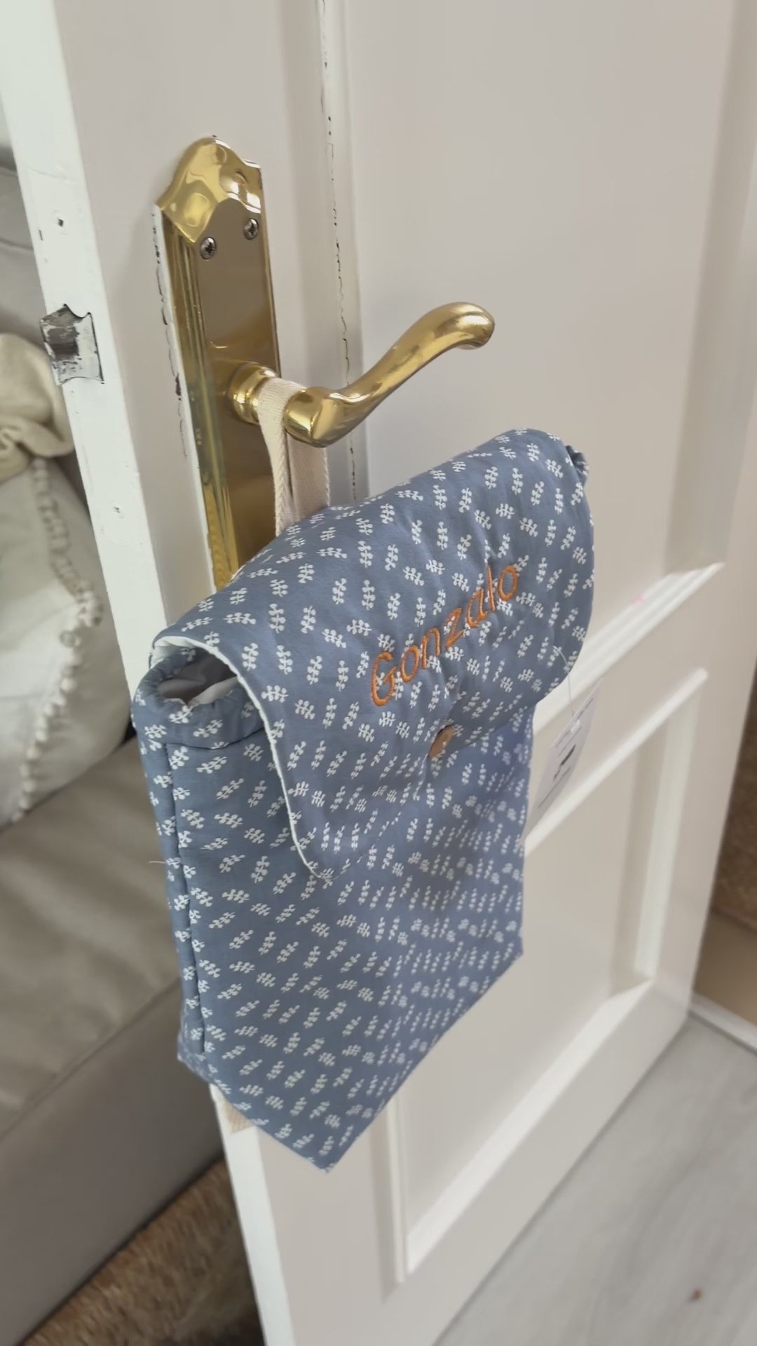 Video al detalle de la mochila para la guardería impermeable por dentro, personalizada con el nombre, y de un estampado de ramitas azul.